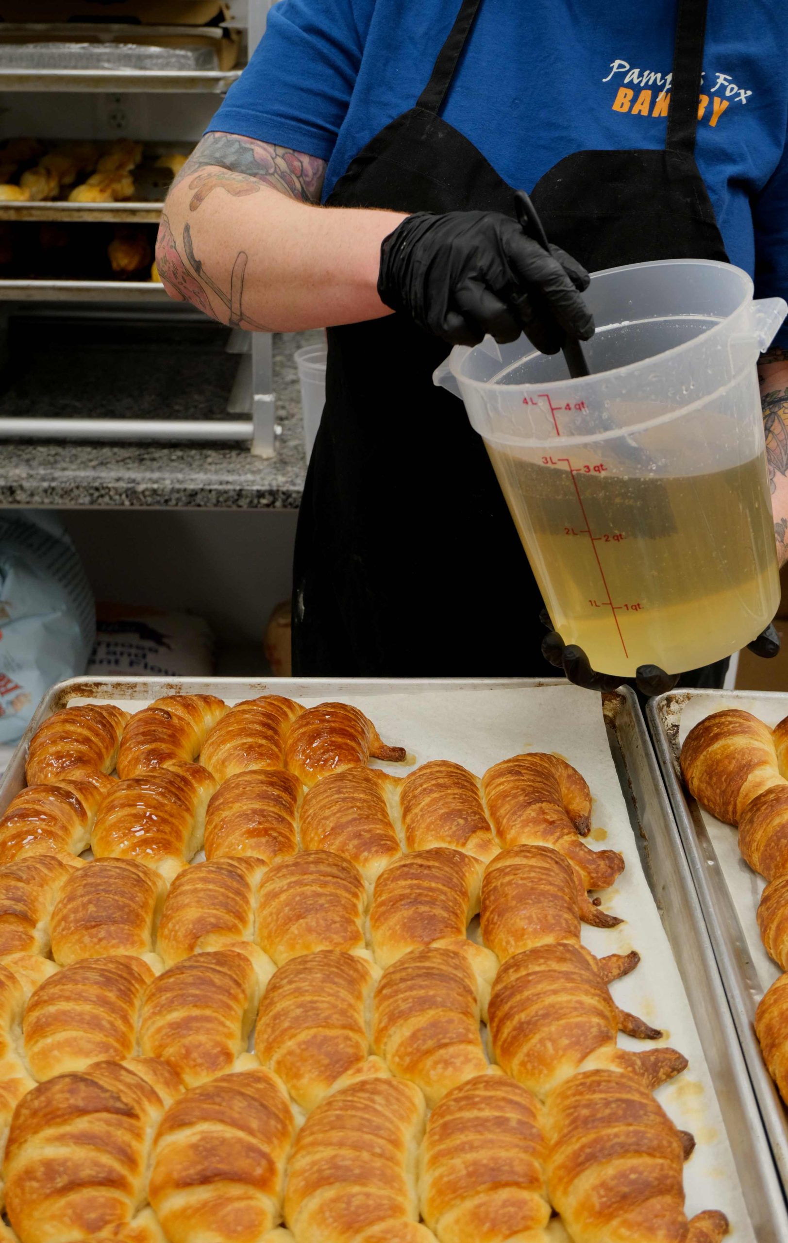 Baker glazing a tray of croissants at Pampas Fox Bakery