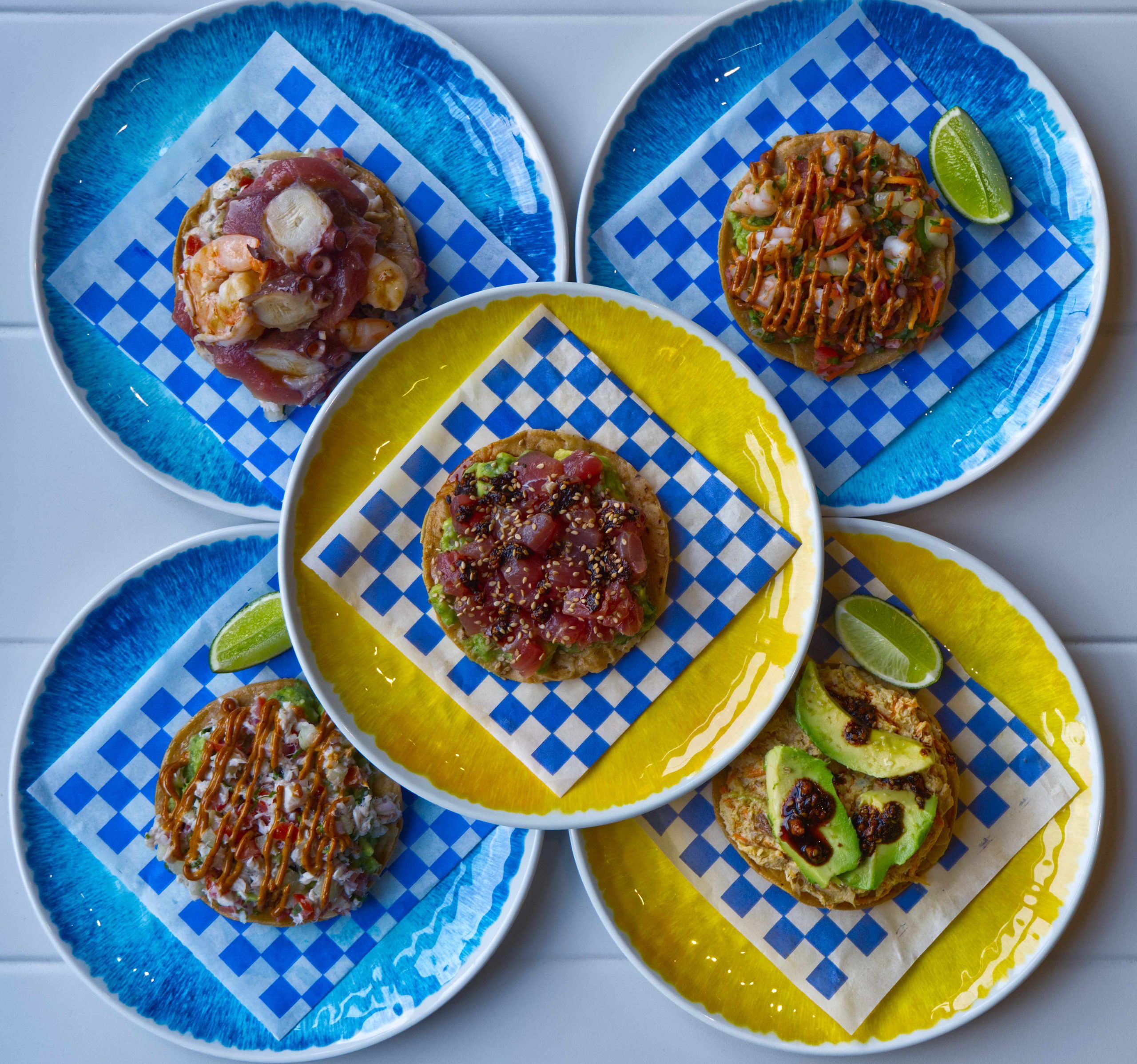 Three tostadas plated overhead for Marea by Apapacho